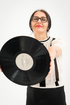 Studio photo of middle aged woman starting getting grey-haired wearing black and white clothes with vinyl record in hands on white background, middle age sexy lady, happy life concept
