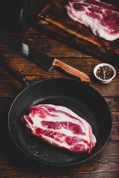 Raw pork neck steak in skillet