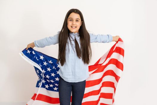 Beautiful patriotic little girl with the American flag held in her outstretched hands