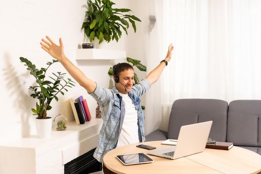 Attractive caucasian businessman having online conversation using laptop and headphones at office desk