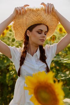 woman with two pigtails in a white dress walking on a field of sunflowers landscape. High quality photo