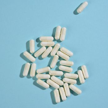 medical powder in white capsules on a blue background. Treatment pills, nutritional supplements