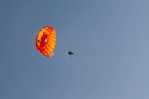 Parachute with flying man against blue sky background