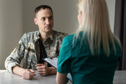Female doctor and worried military officer discussing about problems he has during psychotherapy treatment.