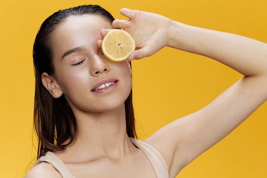 brunette eating lemon in hands smile vitamins diet yellow background