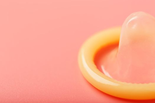 Opened condom on a pink background, close-up, top view.