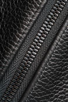 Close-up of the lock on a bag made of genuine black leather, on a dark background