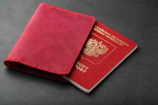 Red passport cover made of genuine leather handmade on a dark background.