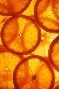 Juicy slices of ripe orange with backlight in the form of cut rings, textural background-substrate