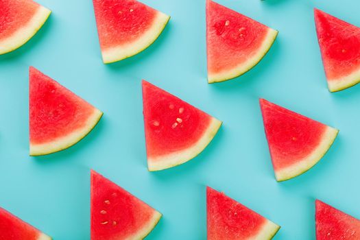 Pattern of slices of fresh slices of red and yellow watermelon on a blue background. Top view