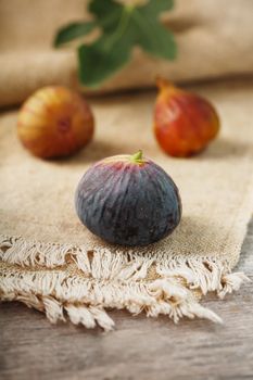 Figs on the table, group of fruits on a wooden farm table with burlap cloth. Slices of fig with pulp. Healthy and tasty fruit