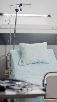 Empty bed in hospital ward with medical equipment