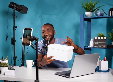 Influencer presenting white mockup gift for fans looking at live video podcast setup