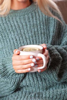 Young woman relaxing tea cup on hands.