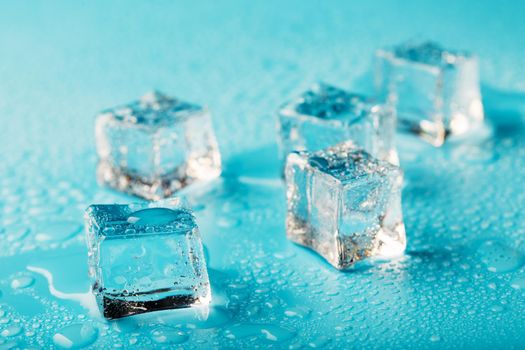 Ice cubes are scattered with water drops scattered on a blue background.