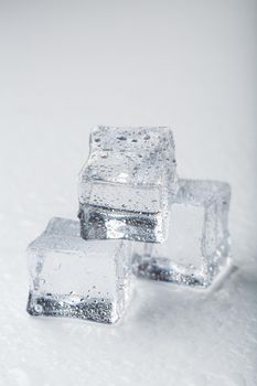 Ice cubes in the form of a pyramid with water drops close - up in macro on a white background.