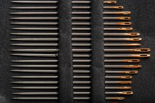 A set of sewing needles on a black background.