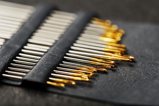 Set of Gold needles on a black background in a row.