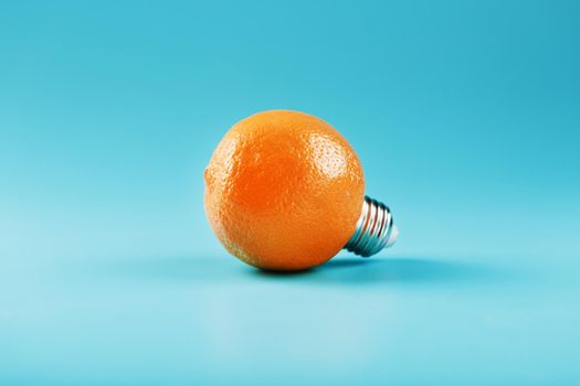 Orange light bulb on a blue background. The concept of fruit ideas