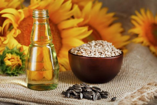 Sunflower oil in a glass bottle and flowers on a wooden background