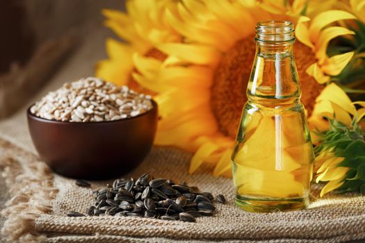 Sunflower oil with sunflower seeds and flowers on a wooden background.