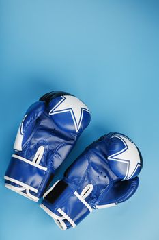 A pair of Boxing blue gloves facing each other on a blue background.