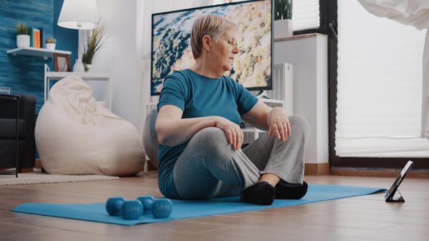 Pensioner watching video of workout lesson with trainer
