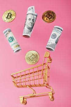 Dollar bills and itkon coins flew out of the Golden Basket on a pink background. Concept