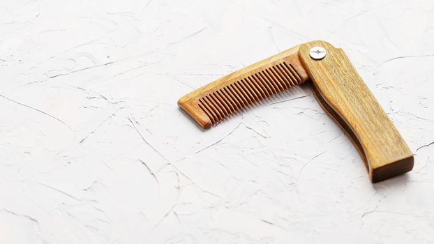 Wooden Sandalwood comb folding on a white textured background.