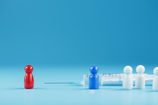 A syringe with a vaccine in the center with a blue and red man with a crowd of whites on a blue background.