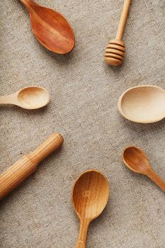 Natural wood spoons in a row on burlap fabric. Natural natural materials.