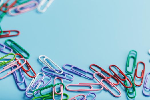 Colored paper clips on a blue background with free space