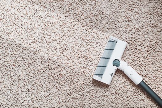 A white turbo brush of a cordless vacuum cleaner on the carpet. Indoor With a clean stripe