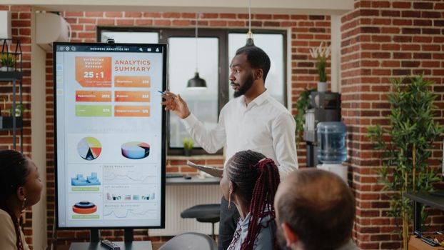 Business man using monitor to do financial presentation, explaining growth and development to coworkers in boardroom. Employee talking about marketing strategy and data analysis
