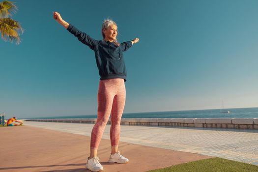 Active joyful adult woman is exercising outdoors