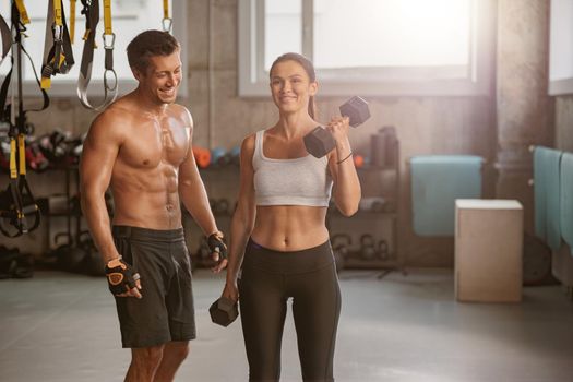 Sporty man in the gym with athletic woman performing sports exercises