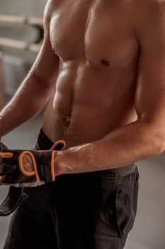 Sporty male with toned body putting on training gloves