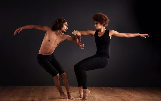 Elegance and balance. A female and male contemporary dancer performing a dramatic pose in front of a dark background.