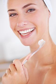 A lovely young lady holding a toothbrush while smiling