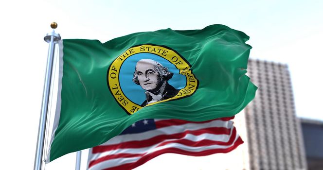 the flag of the US state of Washington waving in the wind with the American flag blurred in the background