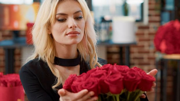 Portrait of romantic beautiful woman smiling and smelling roses feeling in love admiring luxury gift bouquet of roses