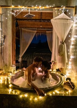 couple in bathroom in bath tub at night with christmas lights, man and woman mid age having romantic night in bath tub in Nan Thailand