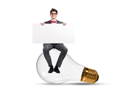 a young businessman sits on a light bulb. with blank banner