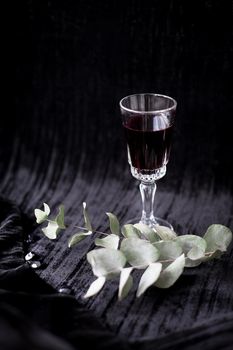 twig and glass of red wine on a black background Velvet