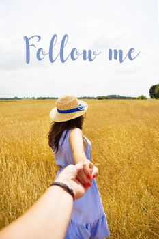 a girl in a blue dress is standing with her back in a wheat field, an inscription follow me