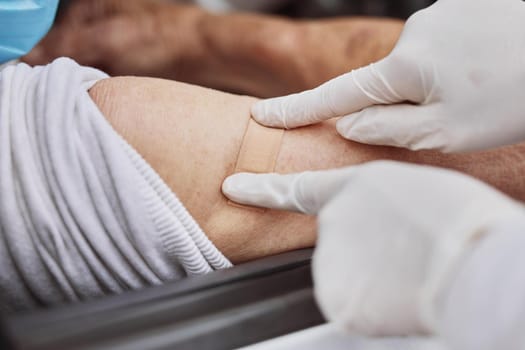 Shot of an unrecognizable healthcare worker applying a band-aid to a patient's arm at a drive through vaccination site