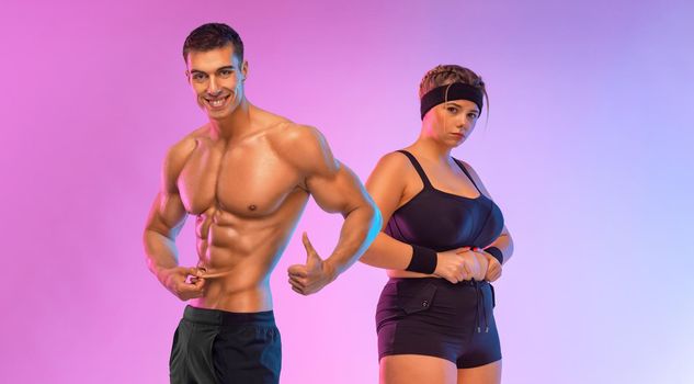 Fit man trainer and fat woman in gym. Body positive and fitness concept.