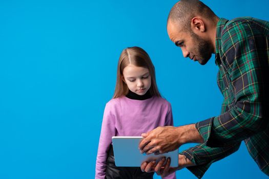 School teacher talking to pupil using digital tablet on blue background