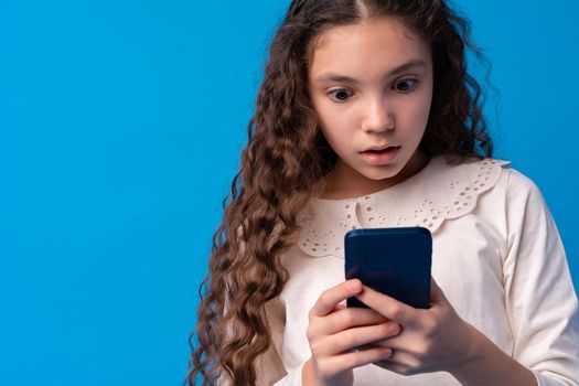 Portrait of a teen young girl using smartphone over blue background