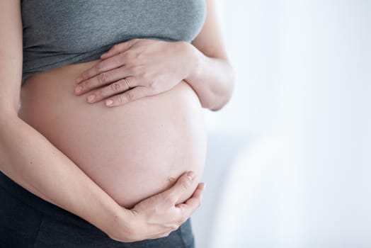 Cropped shot of a pregnant woman standing in her home